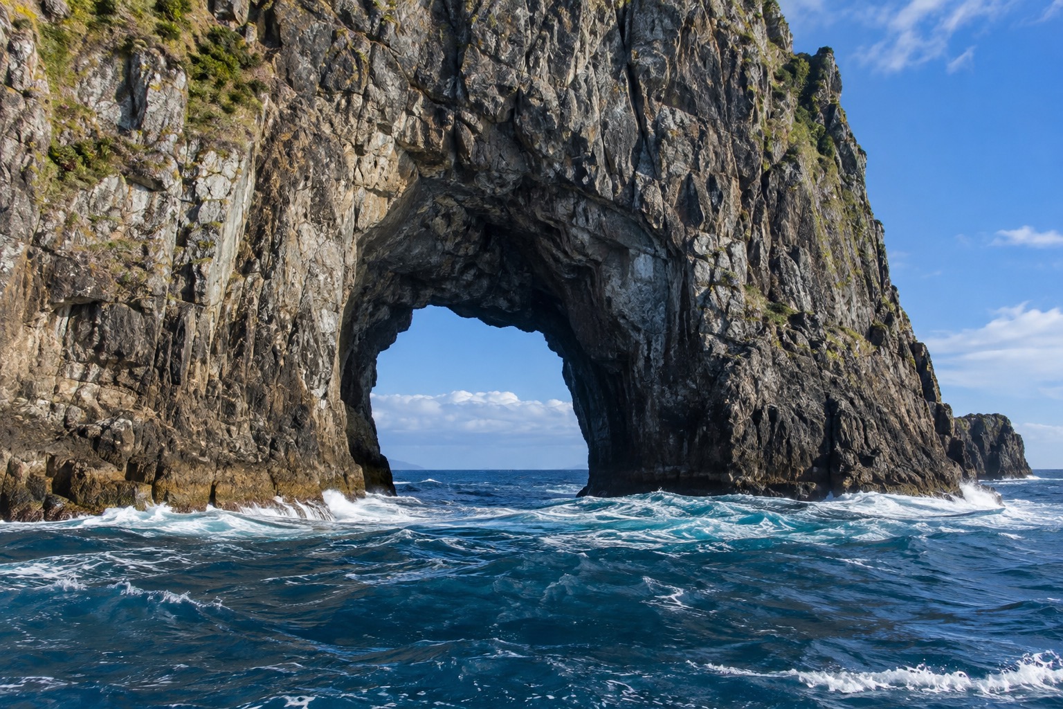 Close view of the natural rock arch through Piercy Island (Motukokako) known as the Hole in the Rock